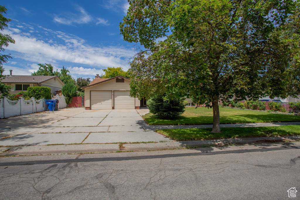View of property hidden behind natural elements with concrete driveway and a garage