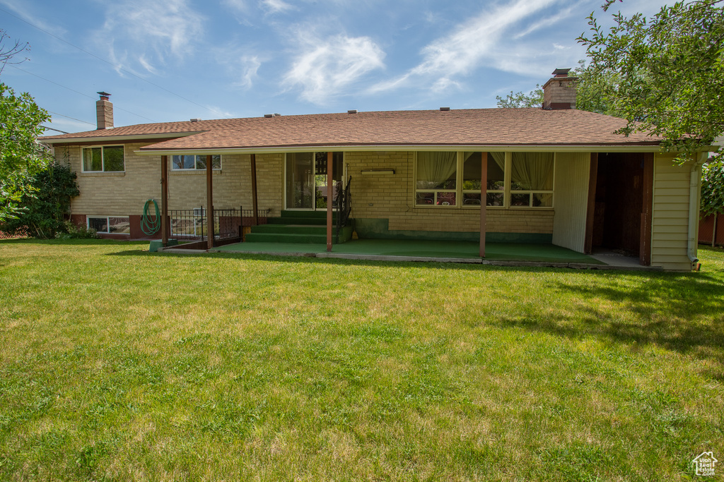 Back of house featuring a chimney and a yard