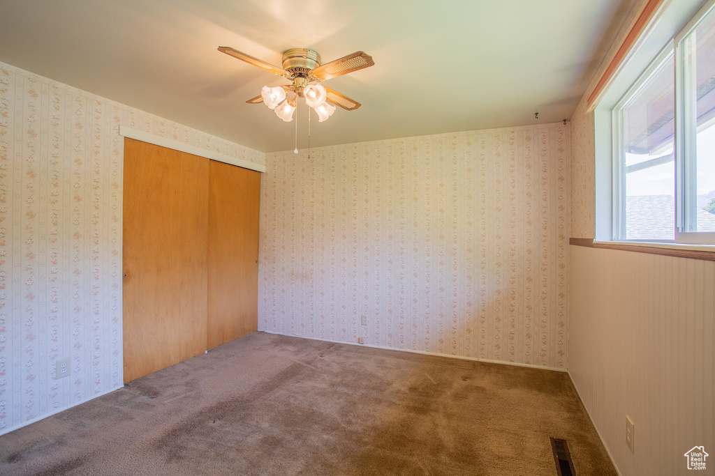 Unfurnished bedroom featuring carpet, a closet, and a ceiling fan