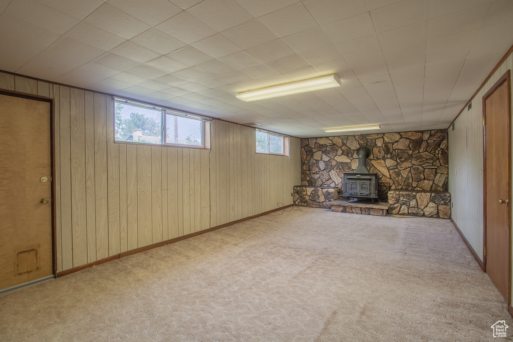 Below grade area featuring wooden walls, a wood stove, and carpet flooring