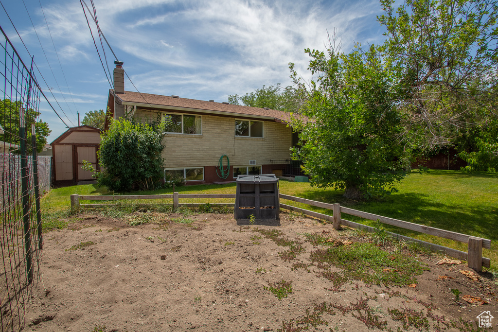 Rear view of property with a storage unit, a chimney, and brick siding
