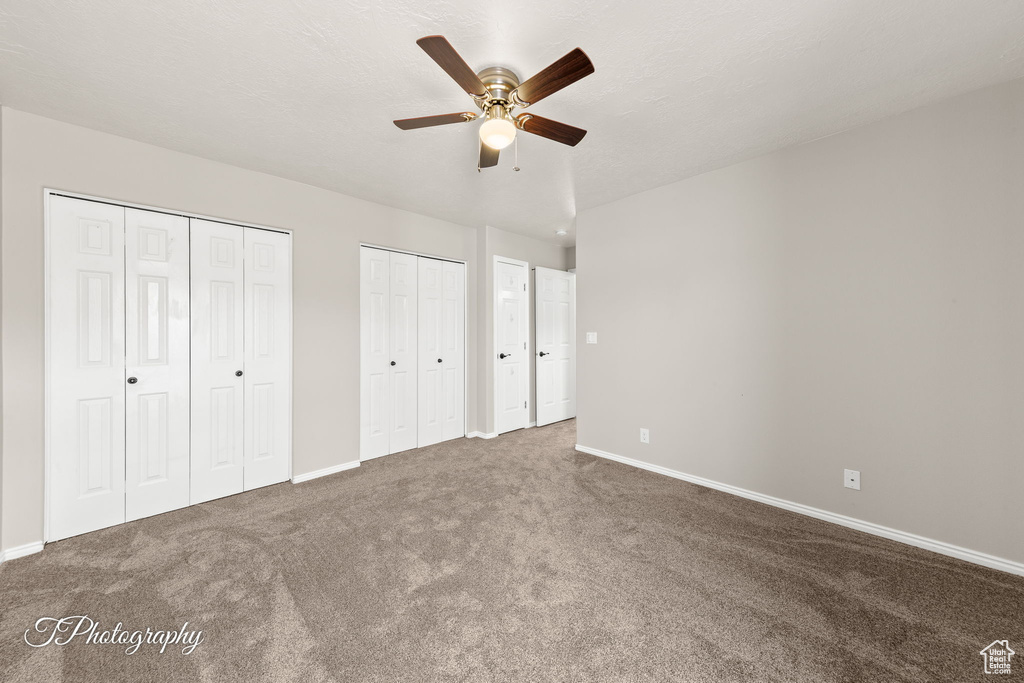 Unfurnished bedroom featuring two closets, carpet flooring, and ceiling fan