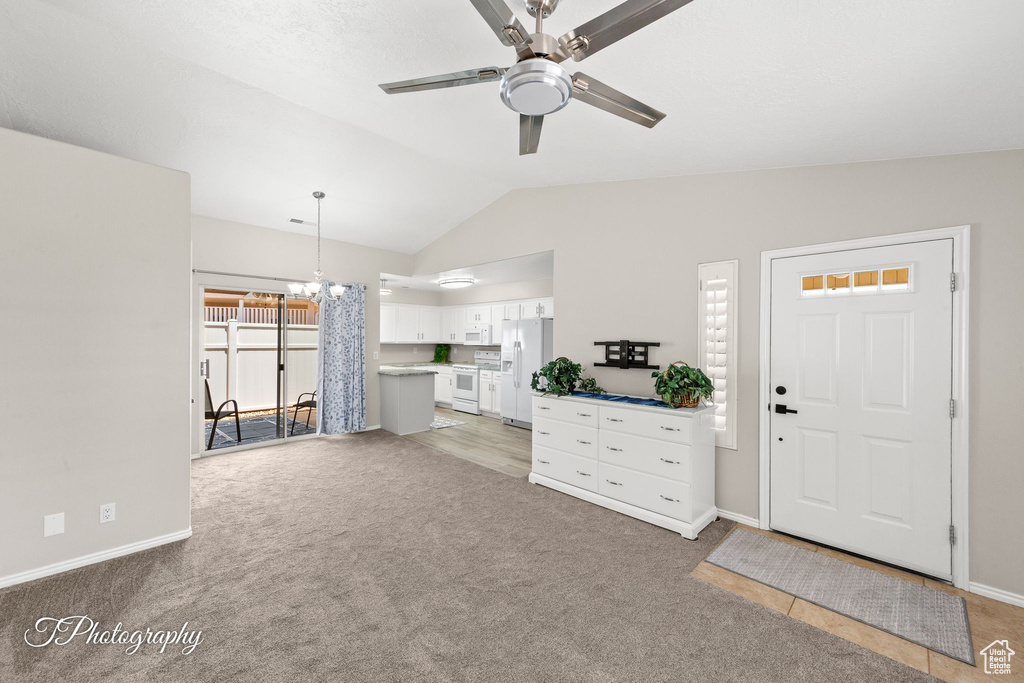 Living room featuring lofted ceiling, a ceiling fan, light carpet, and a chandelier