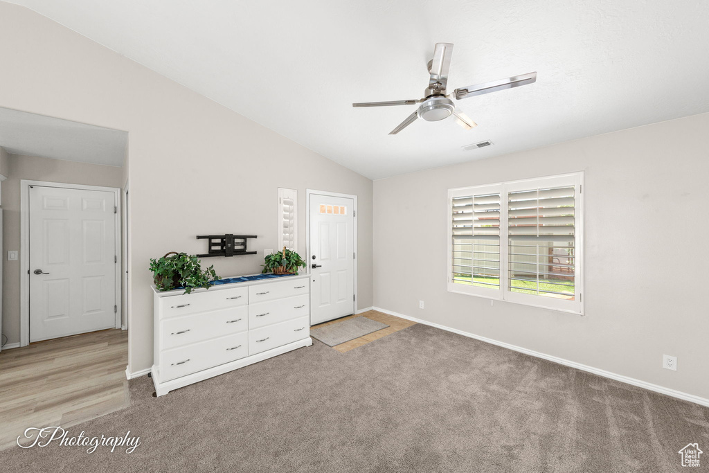 Unfurnished bedroom with light carpet, vaulted ceiling, and ceiling fan