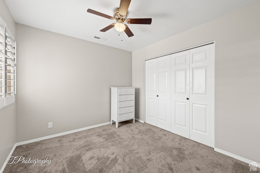 Unfurnished bedroom featuring carpet floors, a closet, and ceiling fan