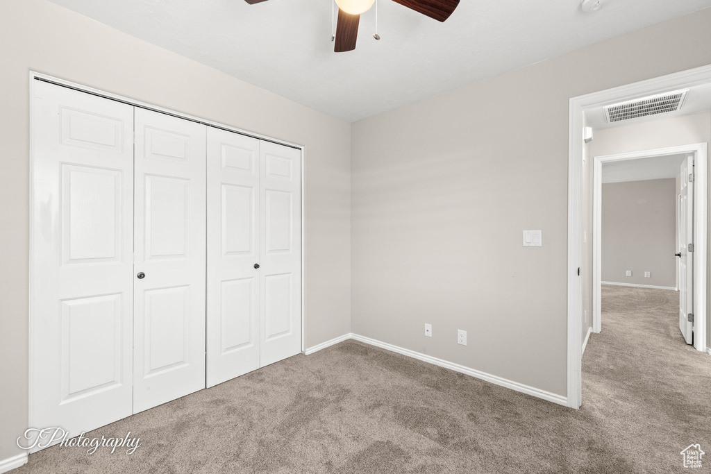 Unfurnished bedroom with carpet floors, a closet, and a ceiling fan