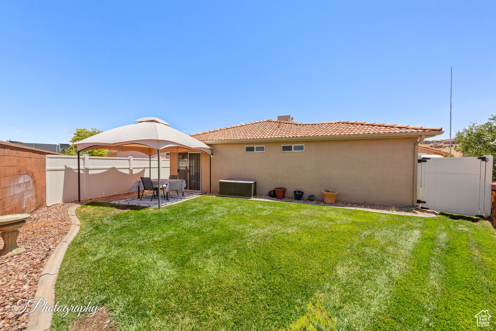 Rear view of property with stucco siding, a tile roof, a fenced backyard, and a patio area