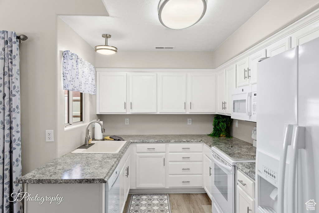 Kitchen with white appliances, white cabinets, and light wood-style flooring