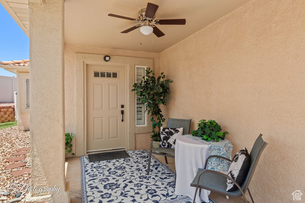 Doorway to property with ceiling fan and stucco siding
