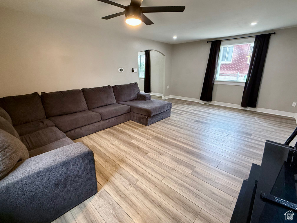Living room featuring ceiling fan, arched walkways, light wood-type flooring, and recessed lighting