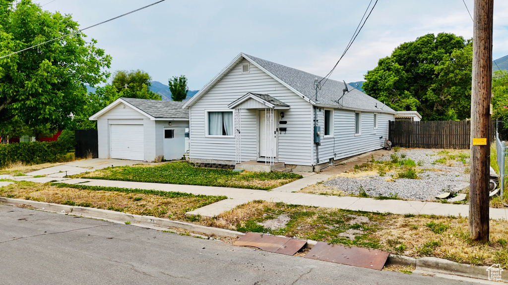 View of front of property featuring a garage, roof with shingles, and concrete driveway