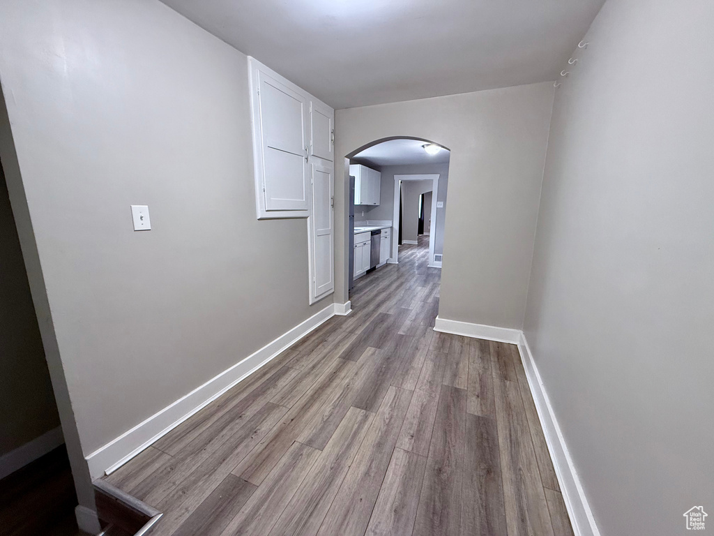 Corridor featuring arched walkways and wood finished floors