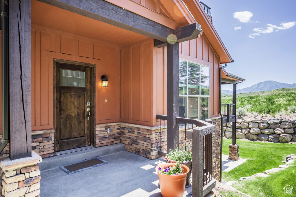 Doorway to property featuring board and batten siding, a mountain view, stone siding, and covered porch