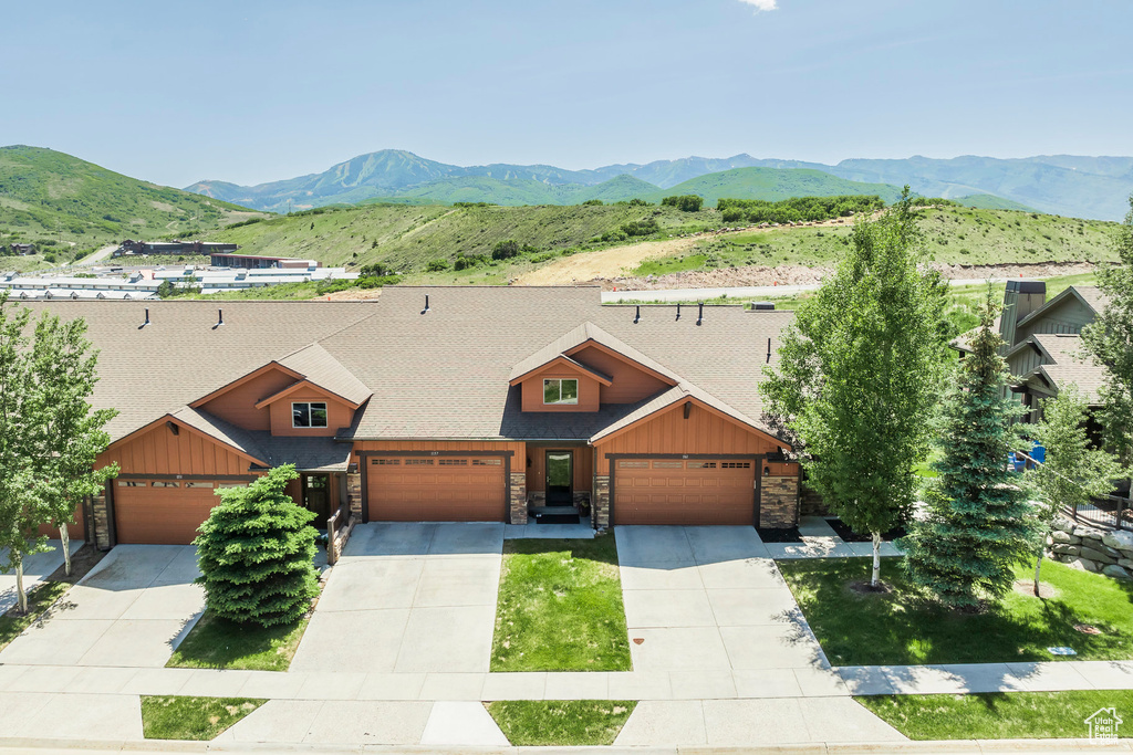 View of front of home featuring stone siding, a mountain view, and a garage