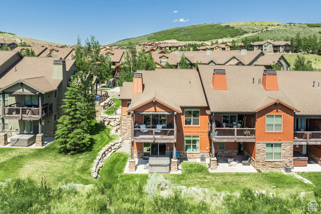 Back of house with stone siding, a residential view, and a patio area