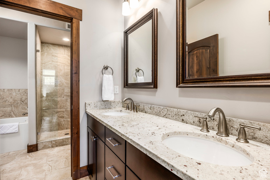 Full bath with double vanity, a garden tub, and a shower stall
