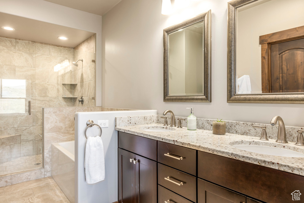 Bathroom featuring a stall shower, double vanity, and a bath