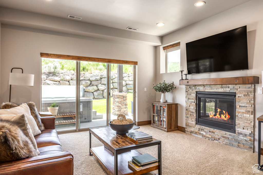 Carpeted living area featuring a stone fireplace and recessed lighting