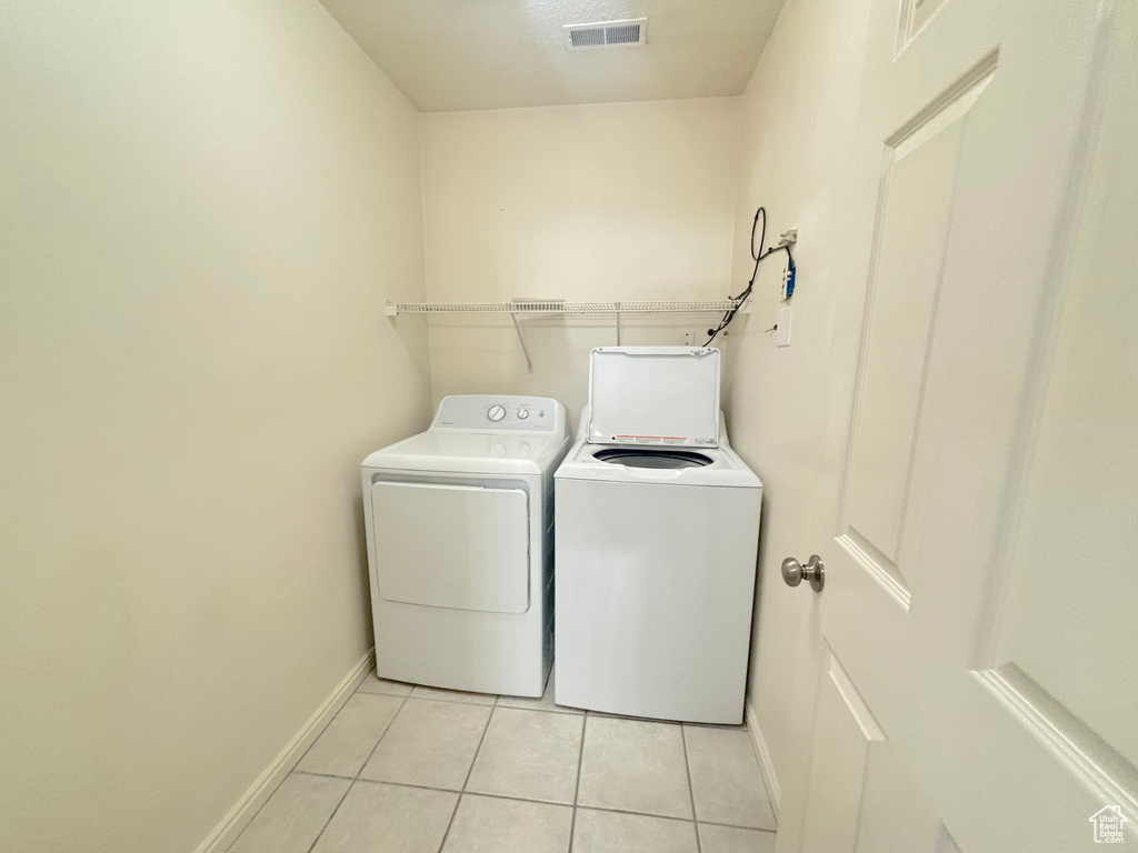 Washroom with washer and clothes dryer and light tile patterned flooring