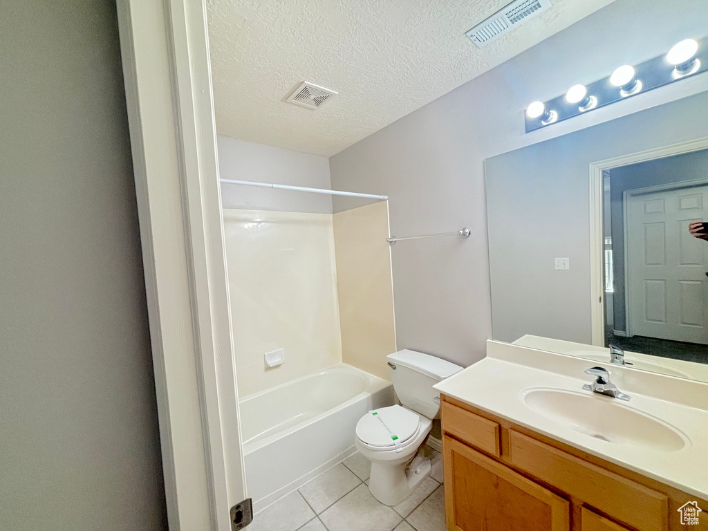 Full bath featuring tile patterned floors, vanity, tub / shower combination, and a textured ceiling