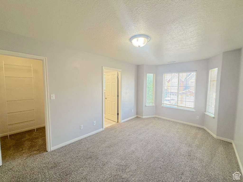 Empty room with carpet floors and a textured ceiling