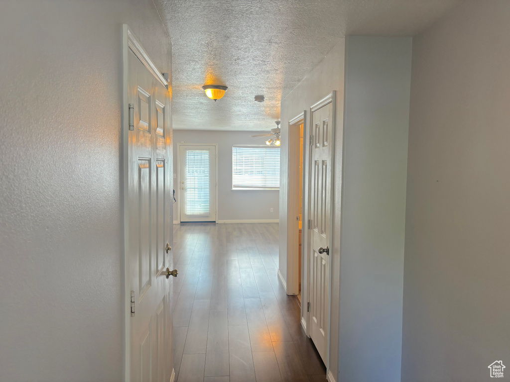 Hall with a textured ceiling and dark wood-type flooring