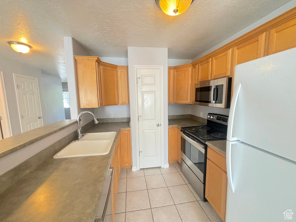 Kitchen featuring stainless steel appliances, a textured ceiling, and light tile patterned floors