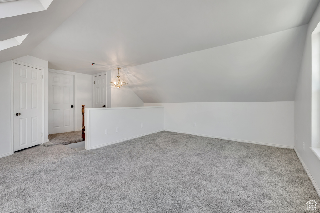 Additional living space with a skylight, lofted ceiling, carpet flooring, and a chandelier