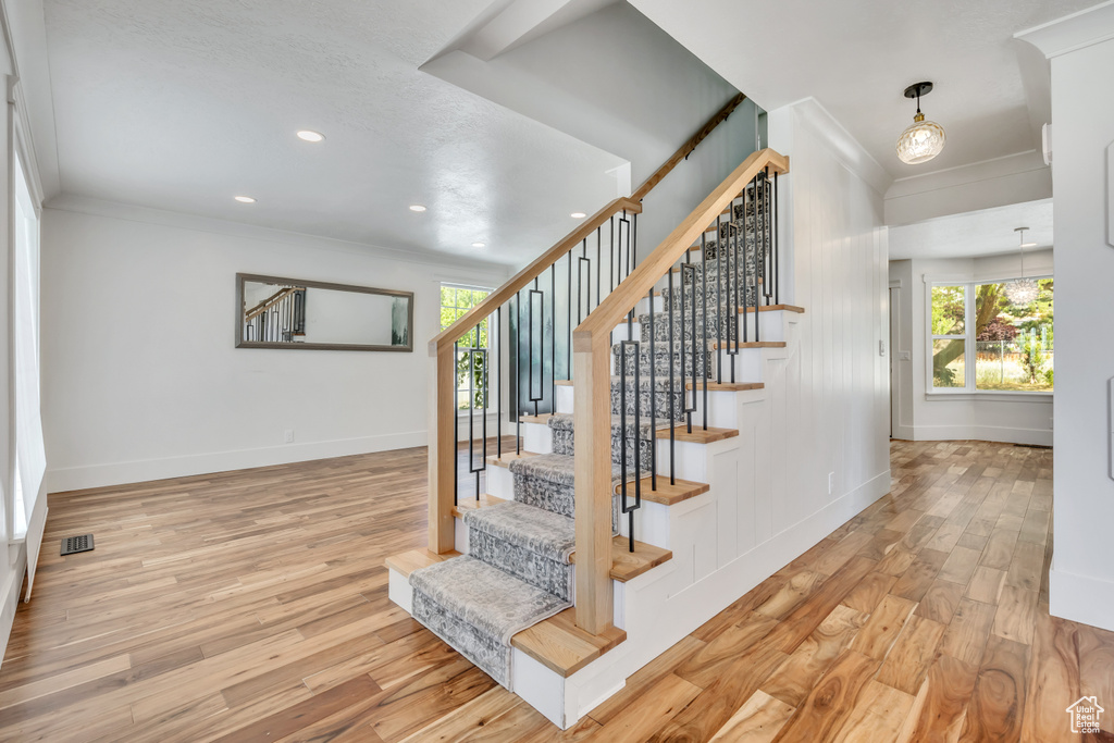 Staircase featuring crown molding, wood finished floors, and recessed lighting