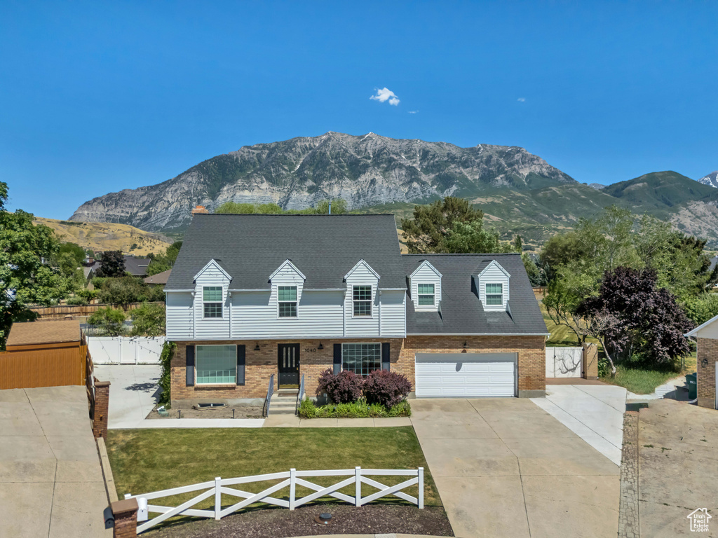 Cape cod-style house with concrete driveway, brick siding, and a mountain view