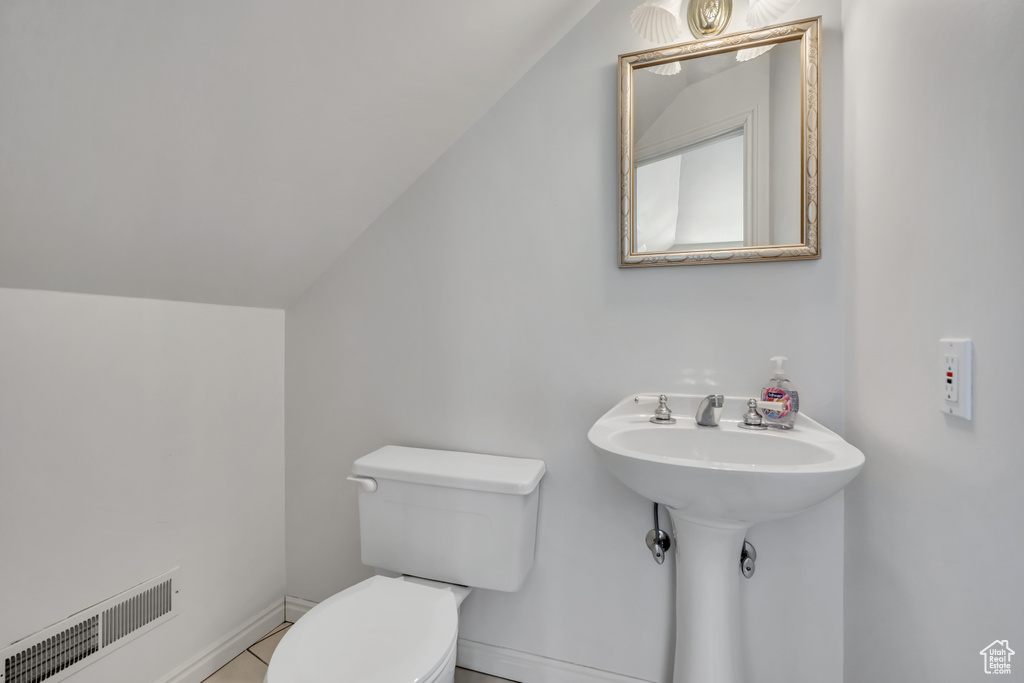 Half bathroom with lofted ceiling and tile patterned flooring