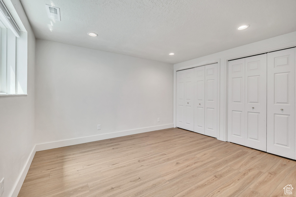 Unfurnished bedroom featuring multiple closets, light wood-type flooring, and recessed lighting