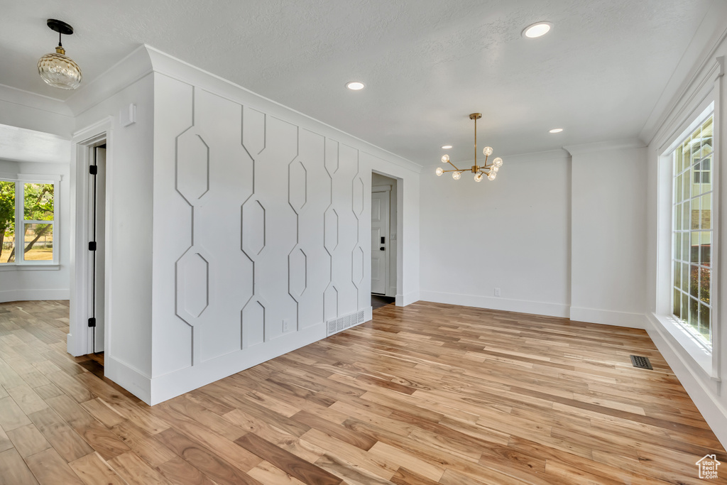 Spare room with a chandelier, crown molding, plenty of natural light, light wood-style floors, and recessed lighting