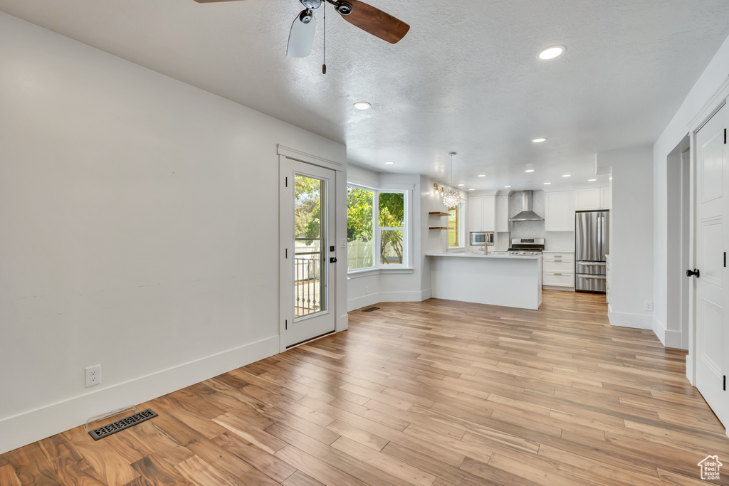 Unfurnished living room with a ceiling fan, recessed lighting, and light wood-style floors