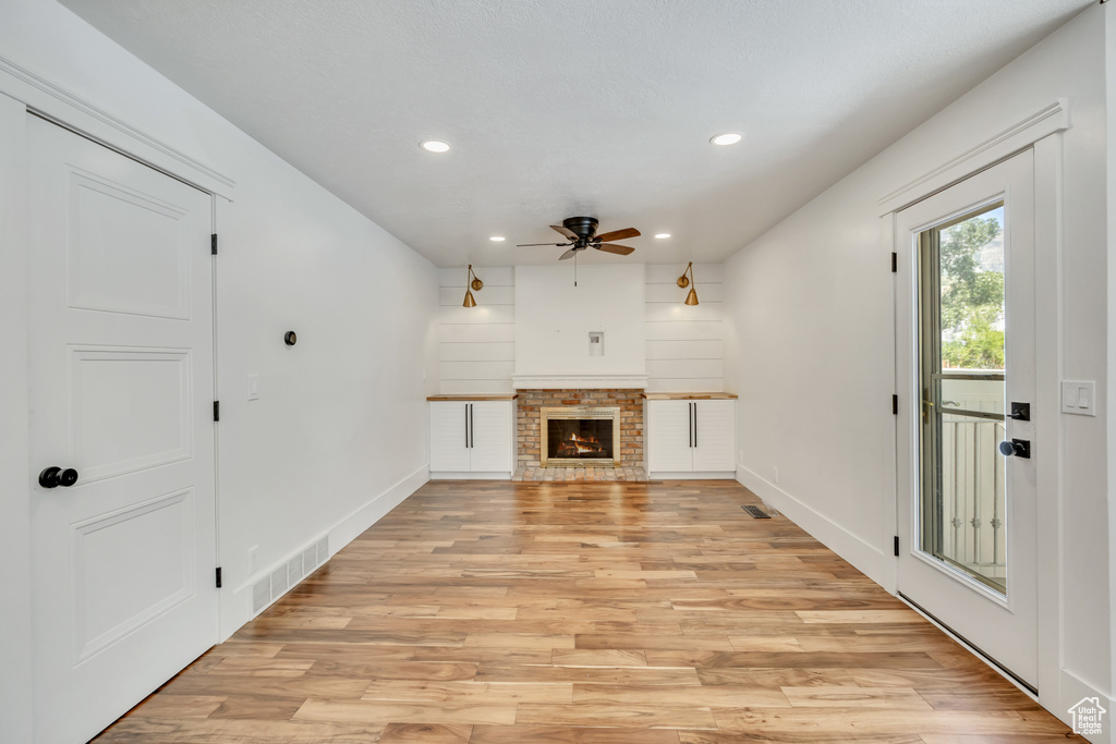 Unfurnished living room featuring a ceiling fan, recessed lighting, light wood-style floors, and a fireplace