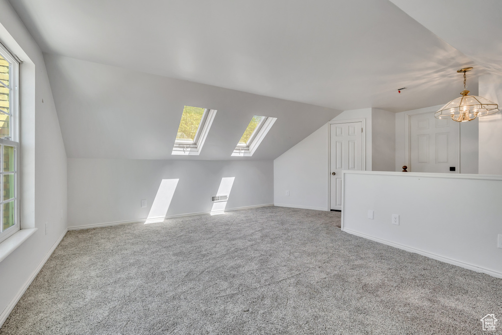 Bonus room featuring lofted ceiling, carpet flooring, a skylight, and a chandelier