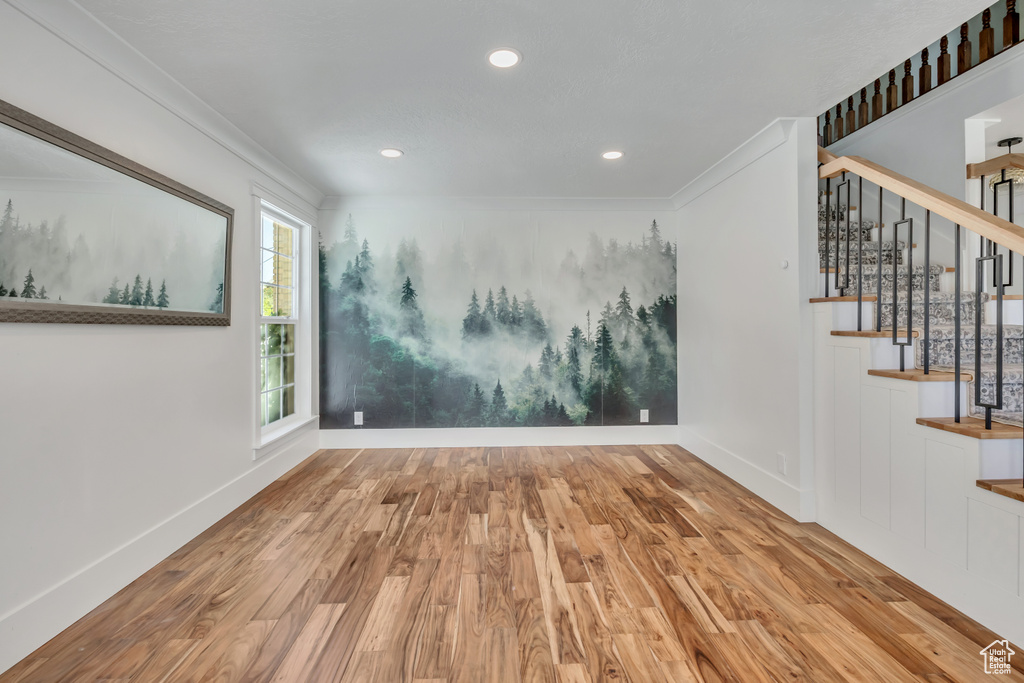 Spare room featuring wood finished floors, stairway, recessed lighting, and crown molding