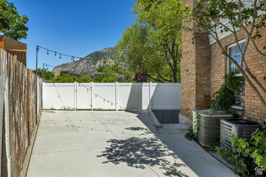 Fenced backyard featuring a mountain view, a patio, and a gate