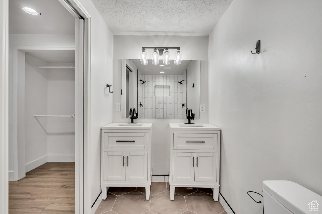 Bathroom with two vanities, a shower, a textured ceiling, and tile patterned flooring