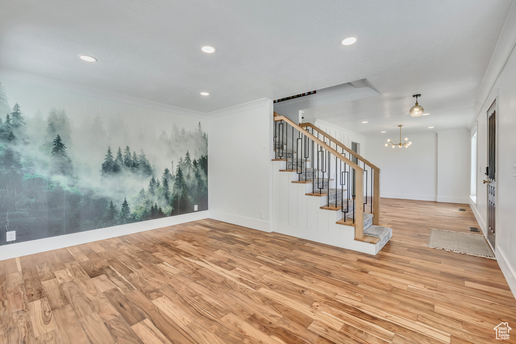 Unfurnished room featuring stairs, wood finished floors, a chandelier, recessed lighting, and ornamental molding