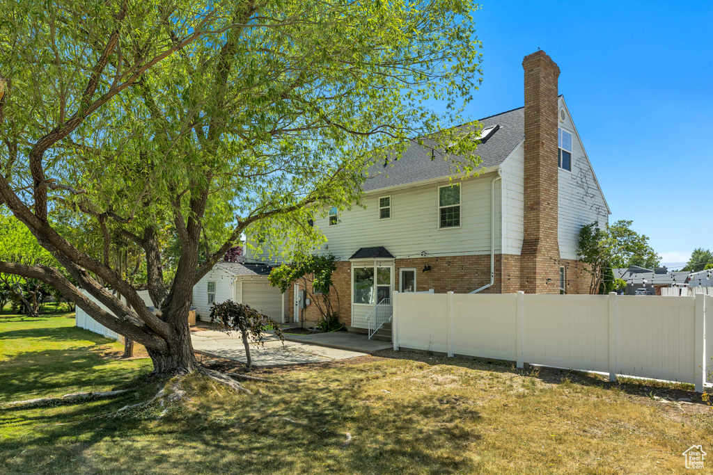 Rear view of house with brick siding, a patio, and a chimney