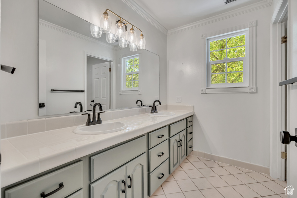 Bathroom with double vanity, crown molding, and tile patterned flooring
