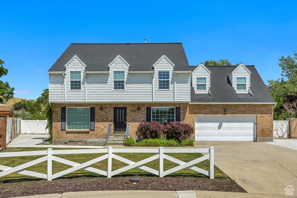 Multi unit property featuring a fenced front yard, concrete driveway, a gate, brick siding, and an attached garage