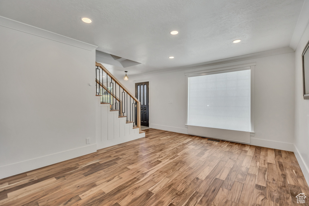 Empty room featuring wood finished floors, stairs, crown molding, and recessed lighting