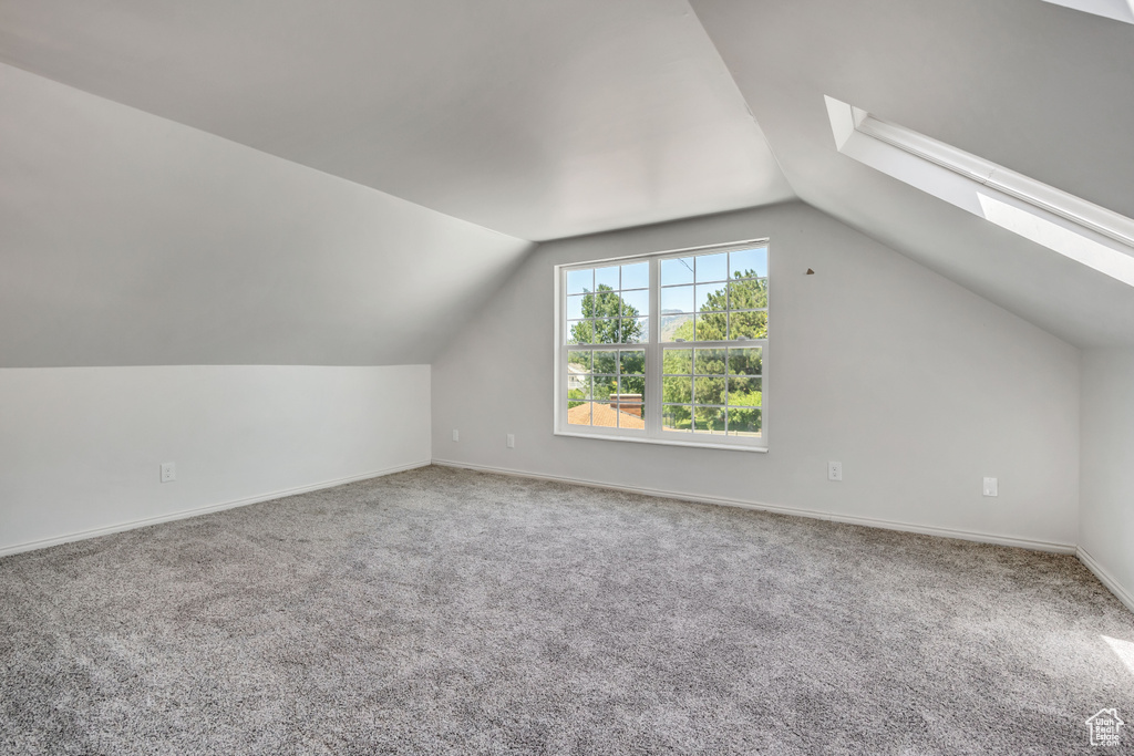 Additional living space featuring a skylight, lofted ceiling, and carpet flooring