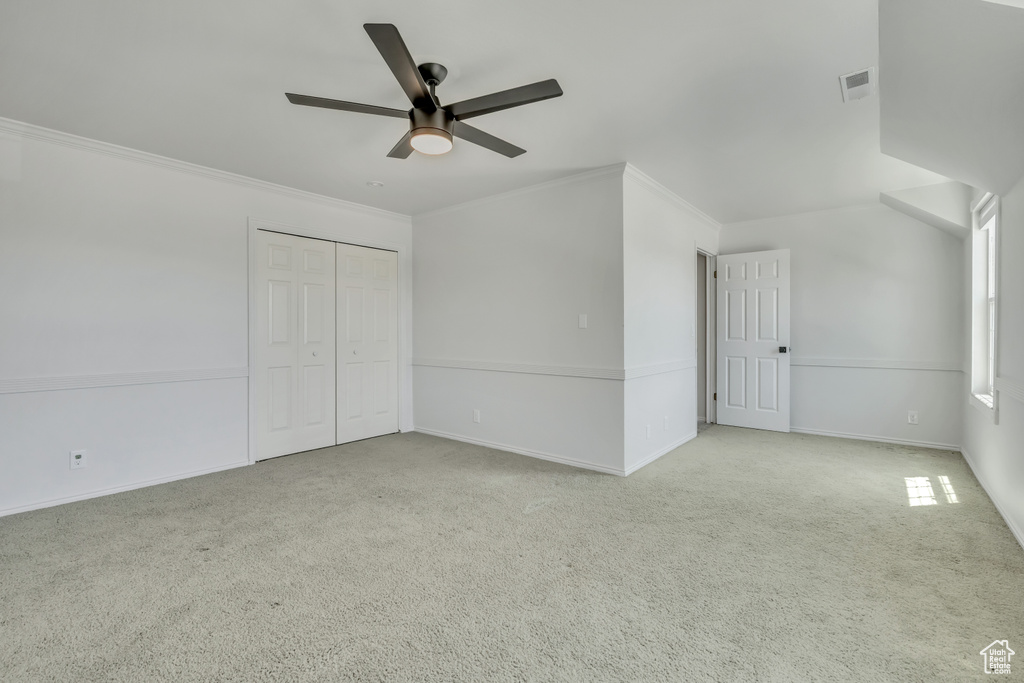 Unfurnished bedroom featuring carpet floors, ornamental molding, a ceiling fan, and a closet