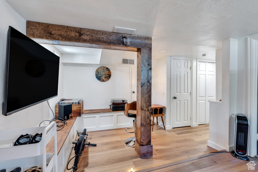 Workout area with light wood-type flooring and a textured ceiling