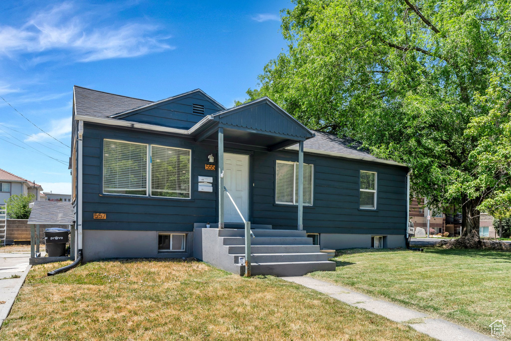 Bungalow featuring a front yard, entry steps, and roof with shingles