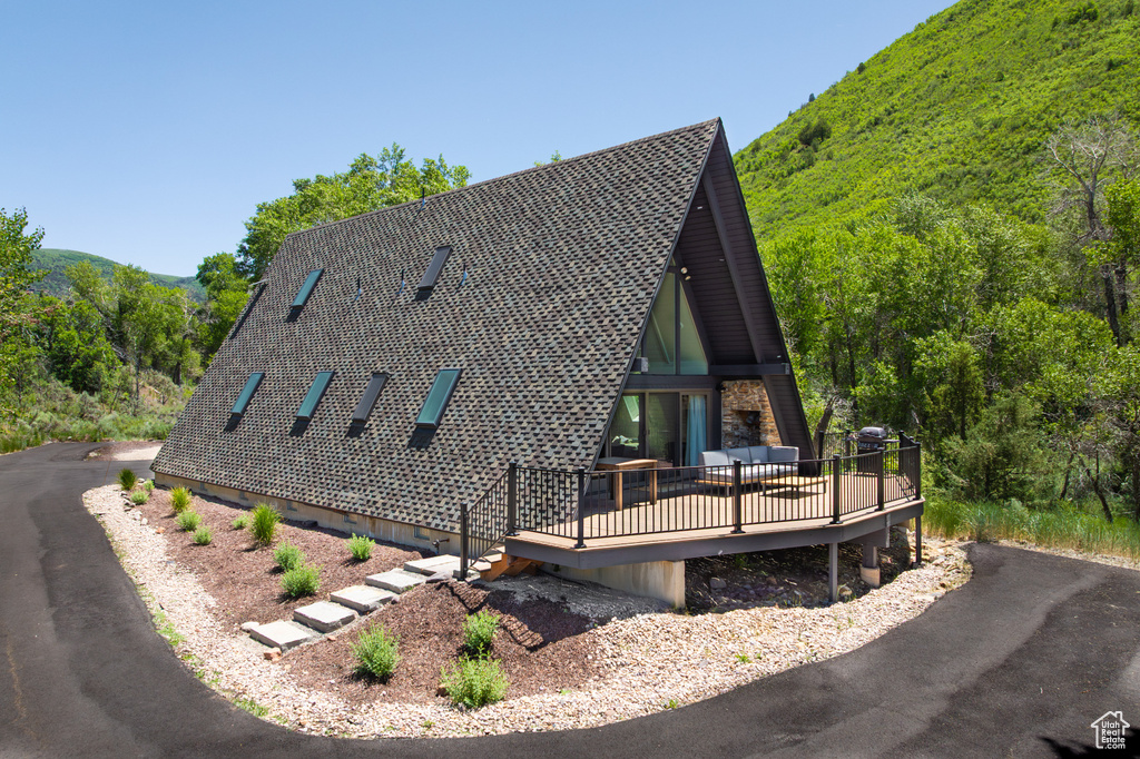 View of front facade with a deck and a wooded view