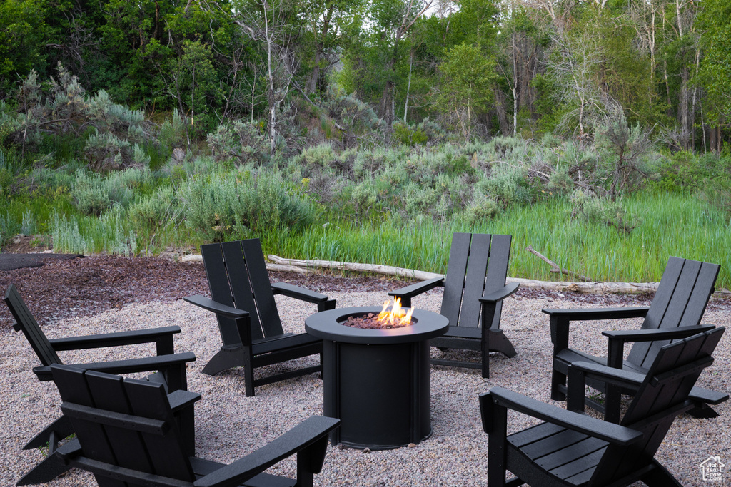View of patio featuring an outdoor fire pit and a wooded view